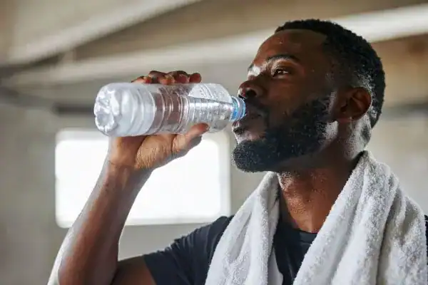 Hydration: The Secret Ingredient for a Toned Stomach and Enhanced Fitness 1 Image of man drinking water to improve hydration Littlehampton after work out.